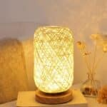 Lampe de chevet rotin décorative au design naturel allumée sur une petite table