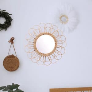 Miroir rotin tendance en forme de fleur sur un mur avec des objets décoratifs autour