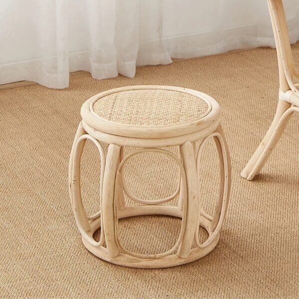 Tabouret rotin beige design et stylé sur le sol avec un rideau blanc en fond