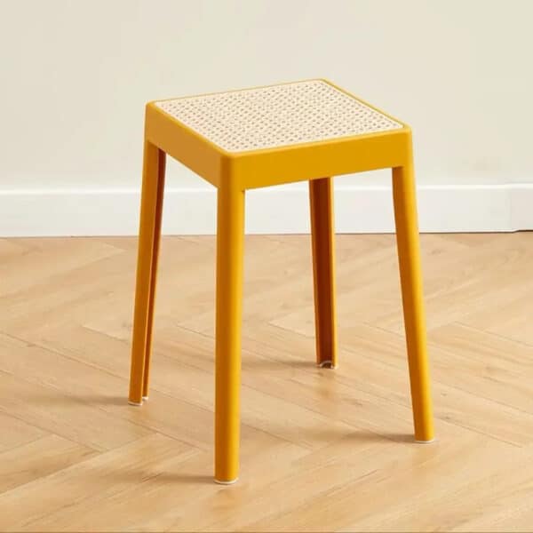 Tabouret rotin élégant et empilable dans une pièce avec du parquet et un mur beige en fond